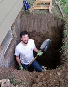 Frank digging a hole with a shovel and pick.